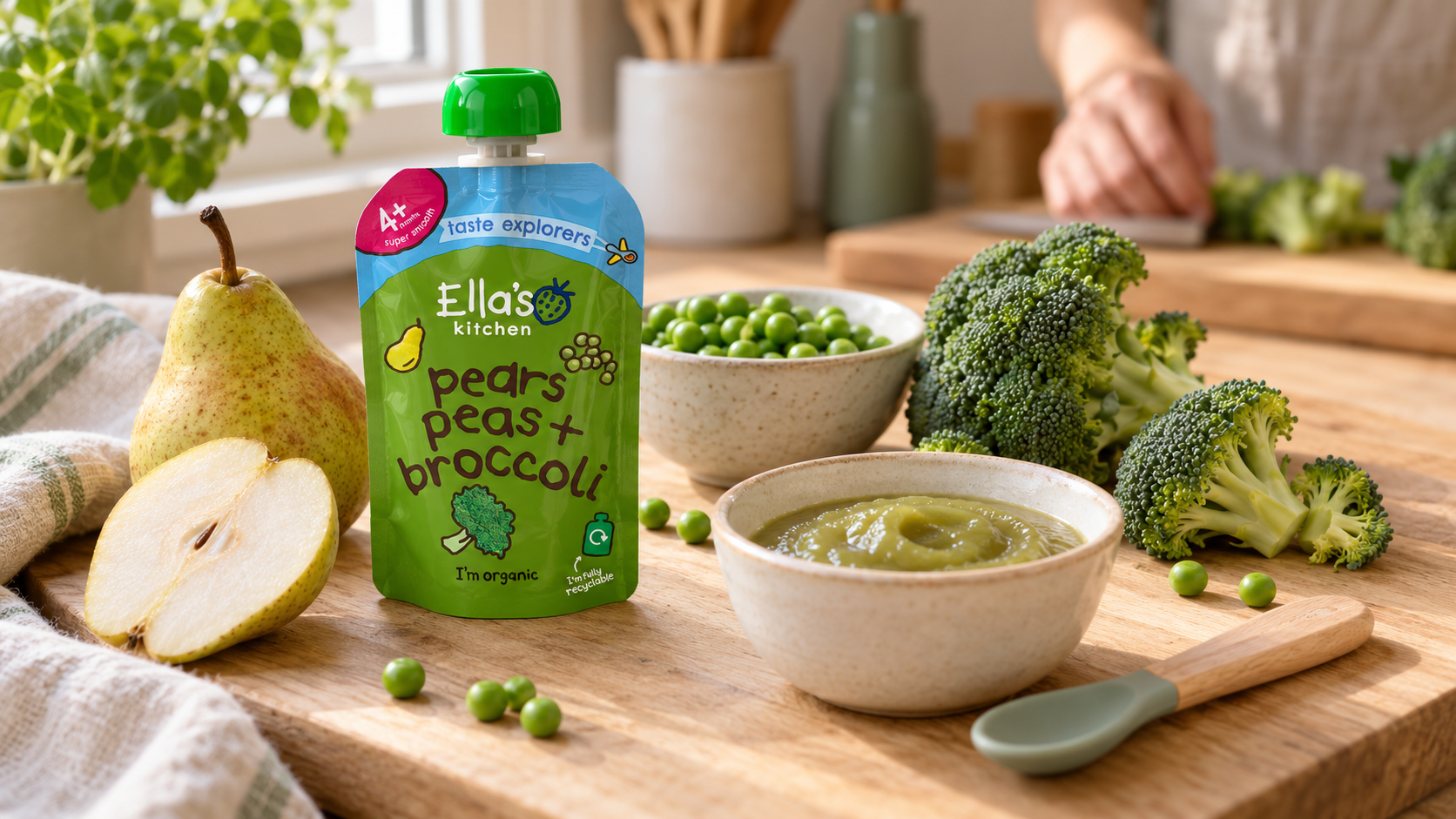 Pouch Ella's Kitchen poire, petit pois et brocoli à côté des ingrédients et d'un bol de purée.